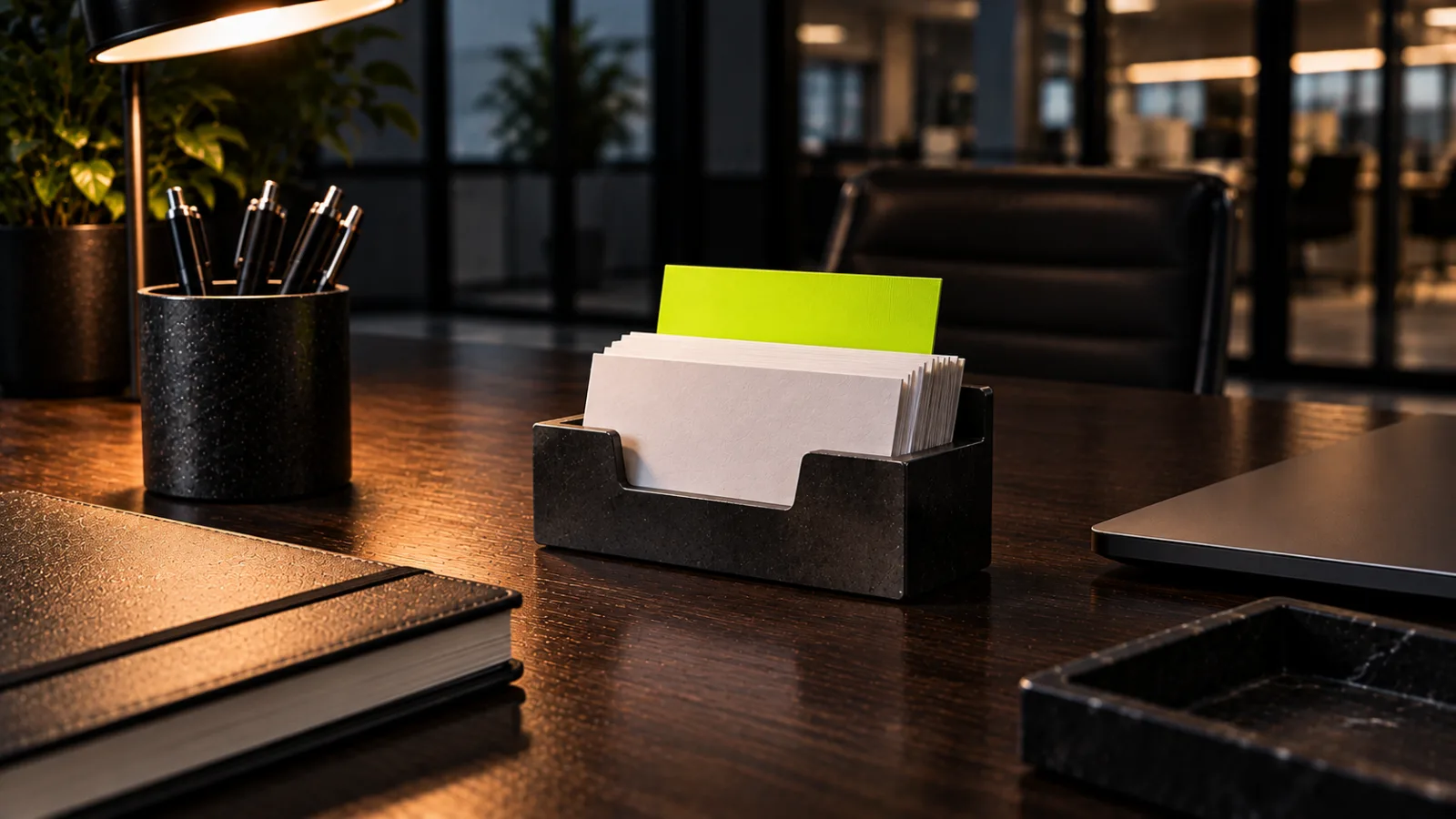 A desk business card holder full of plain white cards with one bright lime card standing up